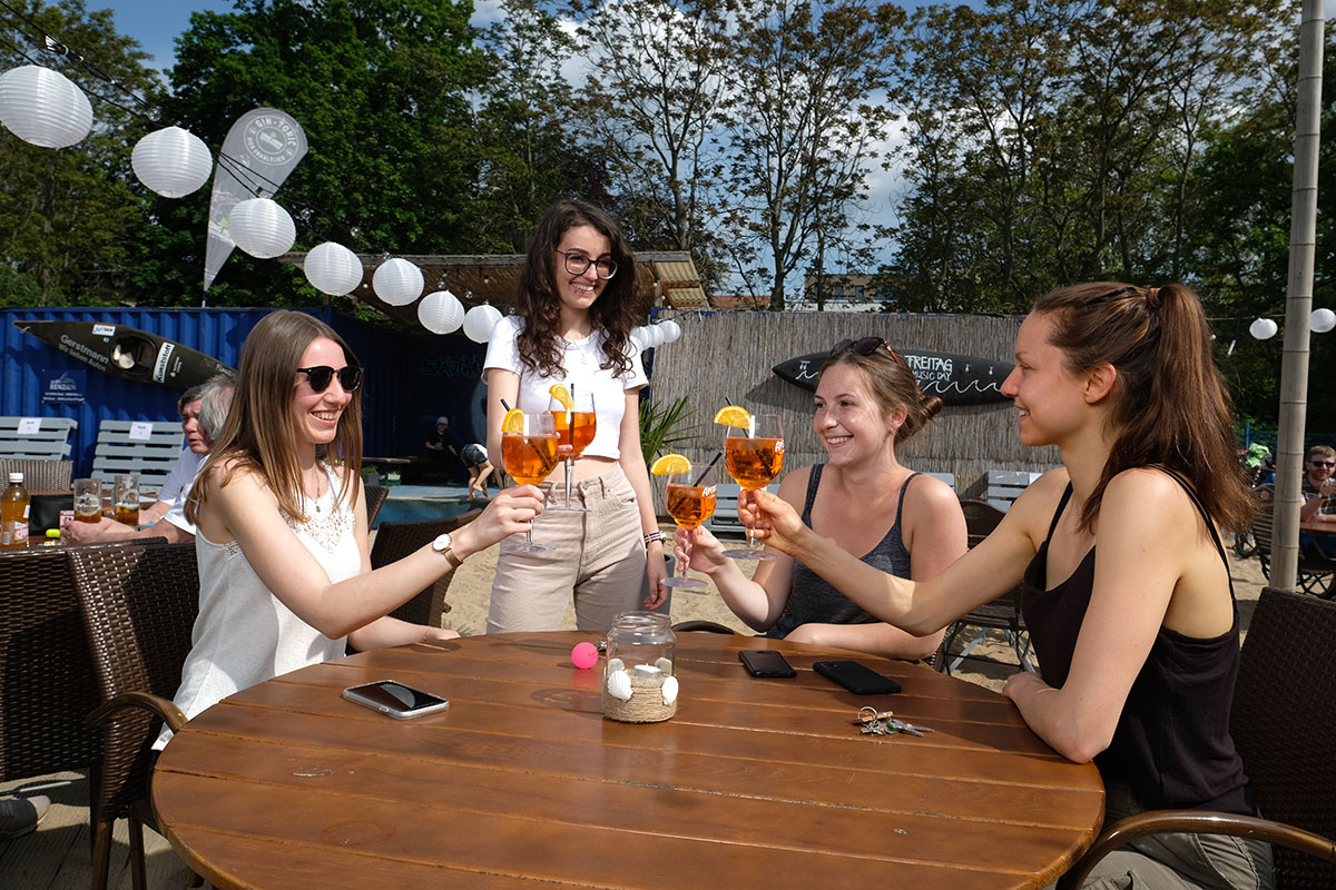 Vier Frauen stoßen mit einem Aperol Spritz im Stadtstrand Leipzig an.
